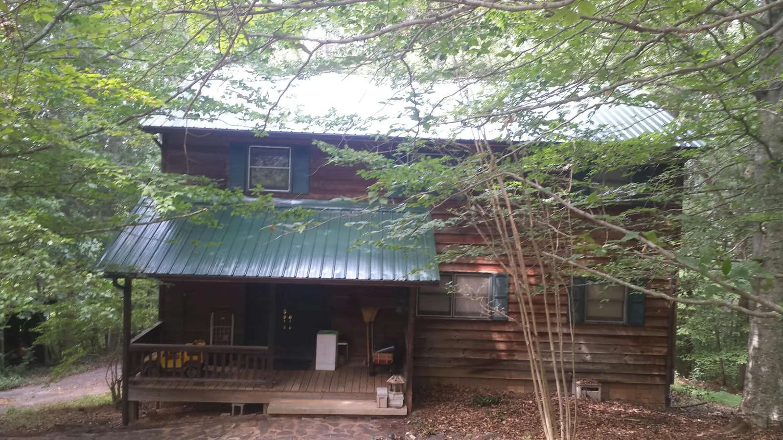 Green metal roof and covered porch on a log cabin in Smiths Station