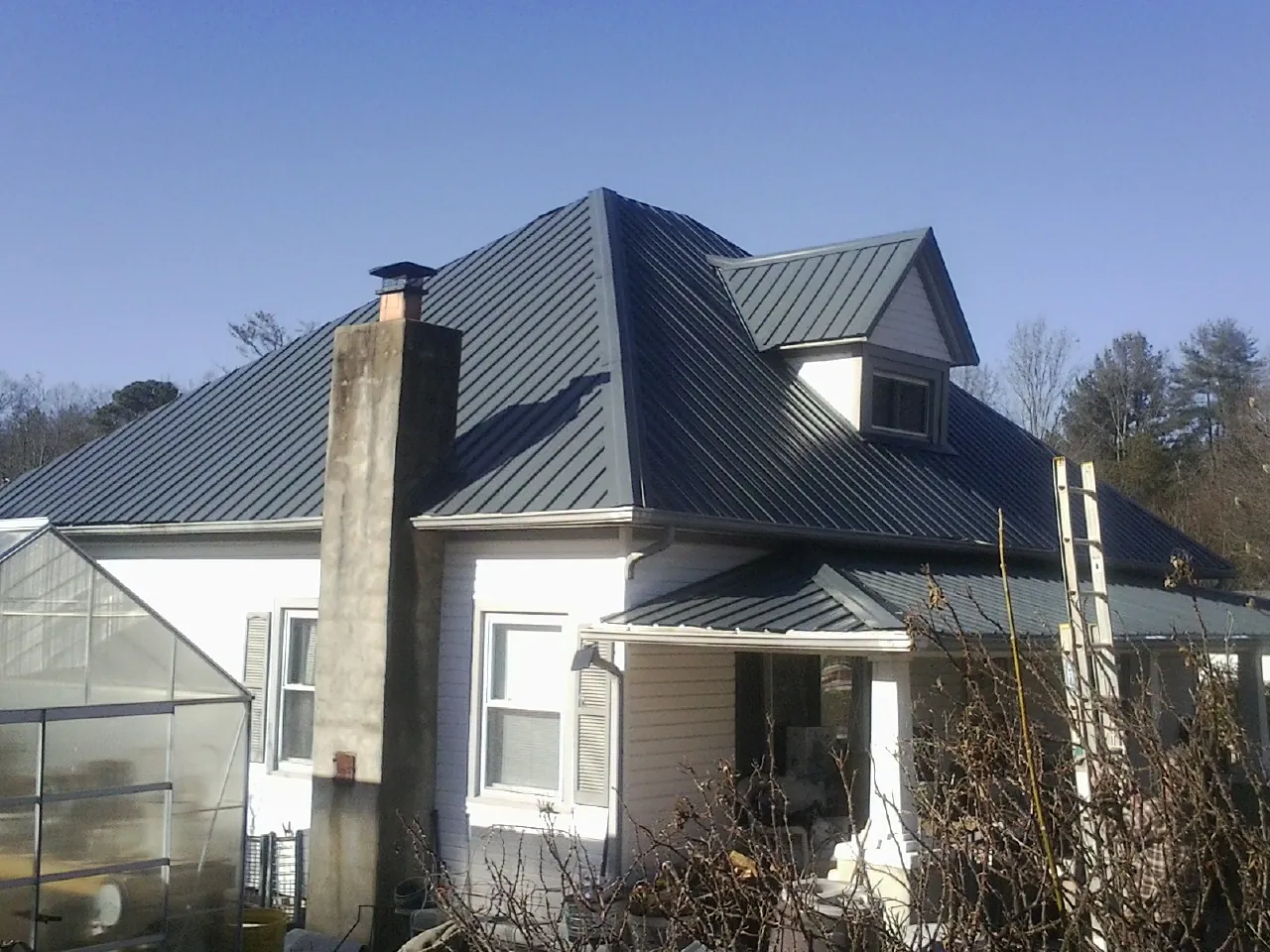 Dark blue standing seam metal roof on a white farmhouse with dormer — Slate & Tile Roof Repair by Roofing Brothers in Smiths Station