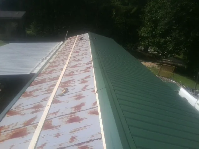 Old rusted panels beside newly installed green metal roofing — Wind Damage Roof Repair by Roofing Brothers in Smiths Station