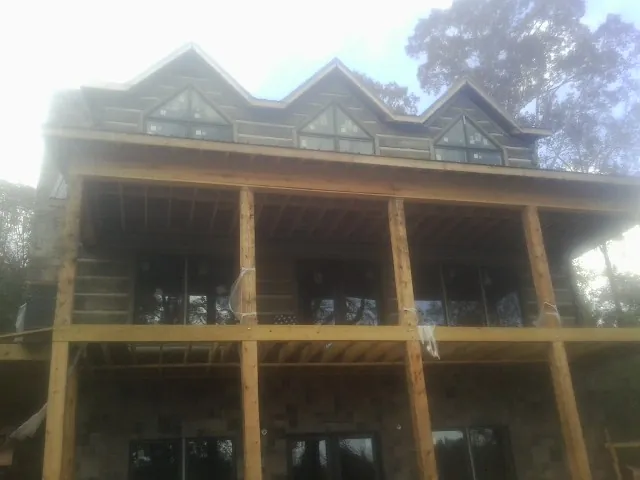 Dormers and porch framing on a large log home under construction — Roof Coating work by our crew in Smiths Station