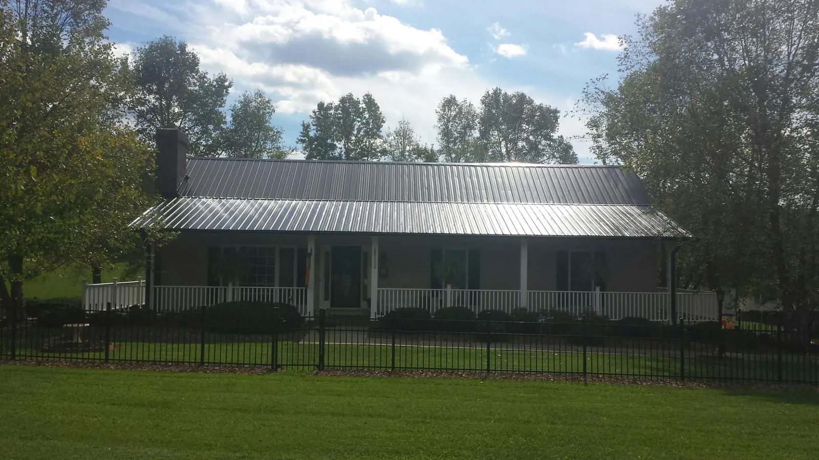 Gray metal roof on a brick ranch with a full width front porch — Gutter Guard Installation work by our crew in Smiths Station