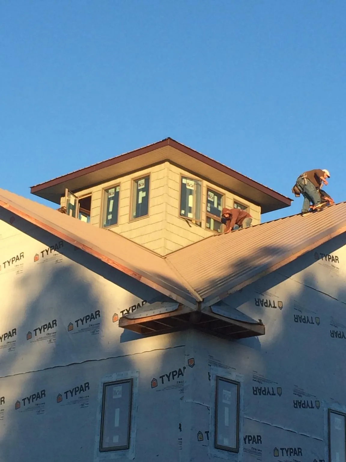 Roofers working around a rooftop cupola on a new metal roof at sunset — Roof Waterproofing in Smiths Station by Roofing Brothers